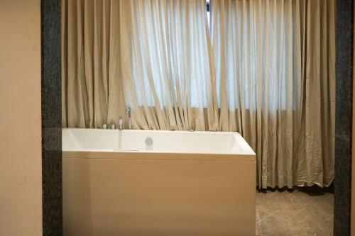 a bathroom with a tub and a large window at Hotel Krushnai Deluxe in Nandre