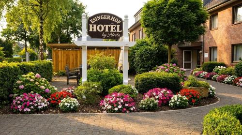 a sign for a hotel with flowers in a garden at Hotel Esingerhof by Alesta in Tornesch