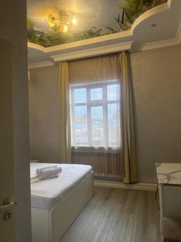a bedroom with a bed with a window and a ceiling at Rodnik in Almaty