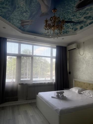 a bedroom with a bed with a ceiling and a window at Rodnik in Almaty