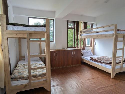 two bunk beds in a room with wooden floors at Mochilero Homestead in Pelling