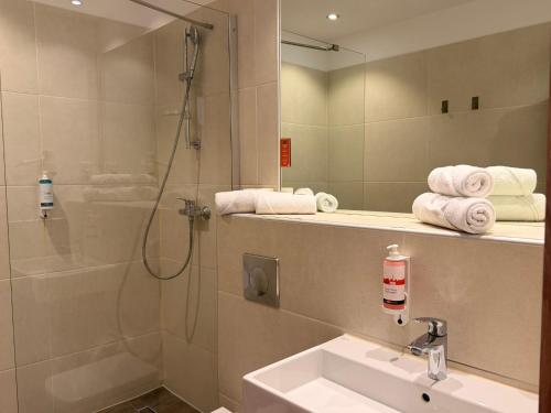 a bathroom with a shower and a sink and a mirror at Motel Plus Berlin in Berlin
