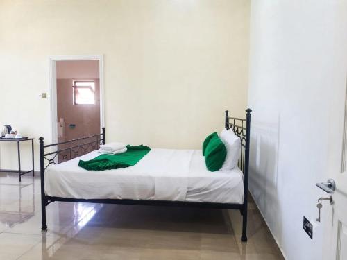 a bed with green pillows on it in a room at Dee Holidays in Moratuwa