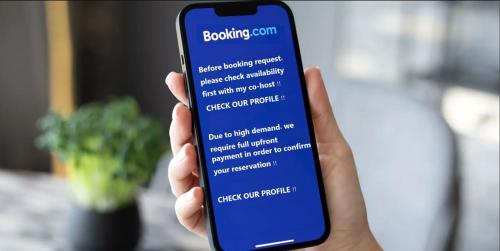 a person holding a cell phone with a booking sign on it at City Choice Apartment in Helsinki