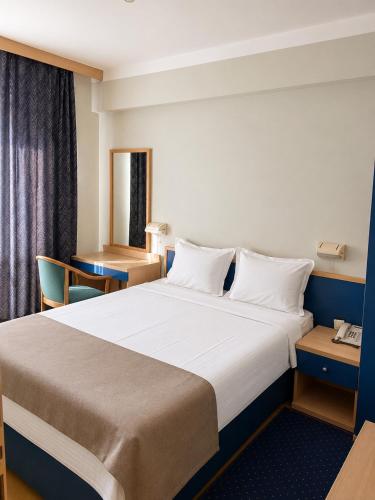 ein Hotelzimmer mit einem großen Bett und einem Schreibtisch in der Unterkunft Hotel Orijent 22 in Laktaši