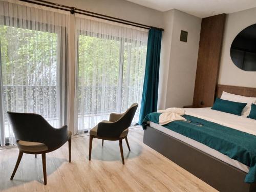 a bedroom with a bed and two chairs and a large window at Uzungol Ada Bungalow in Uzungöl