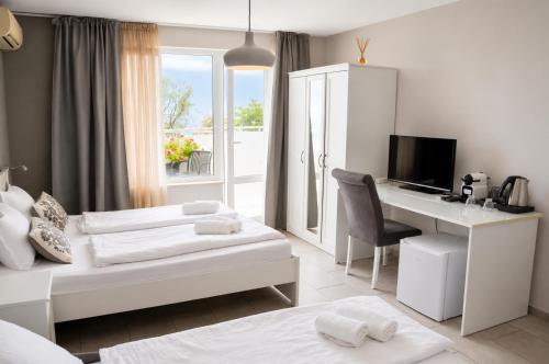 a hotel room with two beds and a desk at Family Hotel Albizia Beach in Varna City