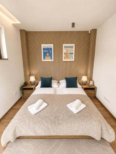a bedroom with a large bed with two towels on it at Villa Porta Verde IV - Infinity pool BBQ Luxury in Balatonalmádi