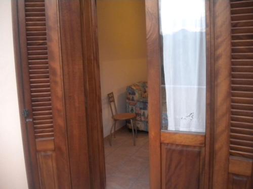 a wooden door leading into a room with a chair at Le case in collina - San Teodoro in Lu Lioni