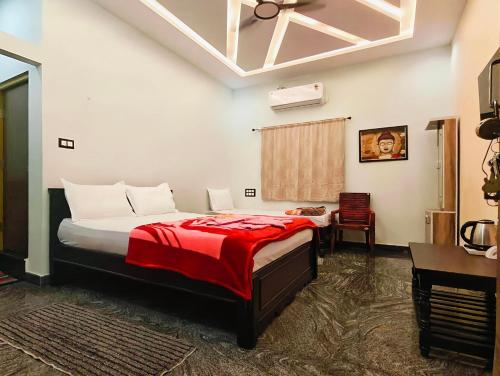 a bedroom with a bed with a red blanket and a desk at Hampi Lake House in New Hampi