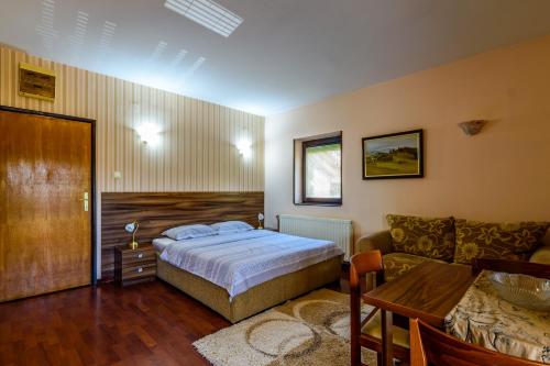 a bedroom with a bed and a couch and a table at Apartment Vila Simovic in Zlatibor