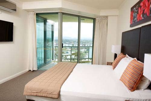 a bedroom with a large white bed and a balcony at Mantra Sun City in Gold Coast
