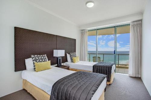 a hotel room with two beds and a large window at Mantra Sun City in Gold Coast