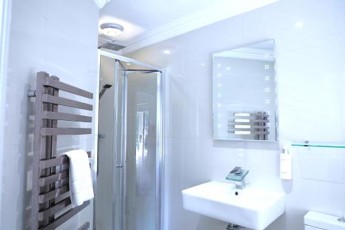 a white bathroom with a sink and a shower at Dalston Hall in Carlisle