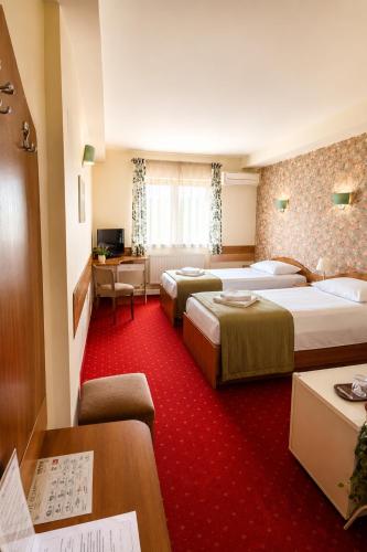 a hotel room with two beds and a desk at Hotel Olimp in Cluj-Napoca