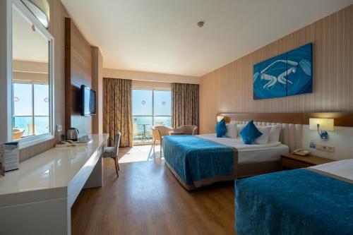 a hotel room with two beds and a desk at Adalya Ocean Deluxe - Ultra All Inclusive in Side