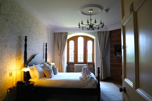 a bedroom with a bed with a chandelier and a window at Dalston Hall in Carlisle