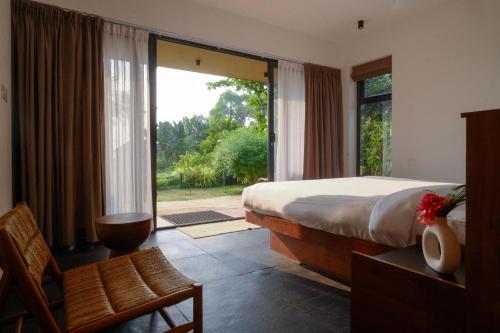 ein Schlafzimmer mit einem Bett und einem großen Fenster in der Unterkunft ETHER Marari Beachfront in Mararikulam