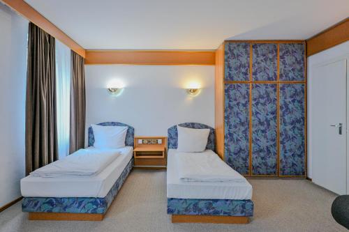 a hotel room with two beds and a window at Hotel Mondial Comfort - Frankfurt City Centre in Frankfurt