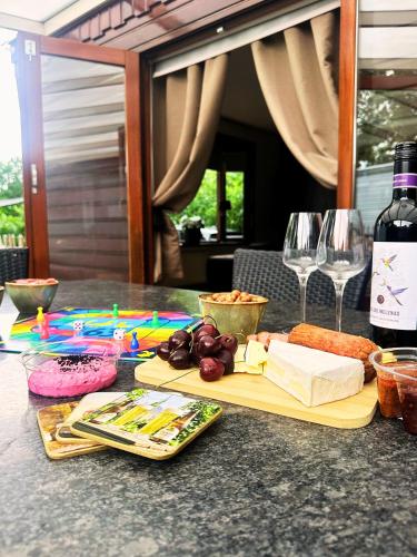 a table with a cutting board with cheese and wine glasses at Rustiek Boschalet Sven Veluwe met Omheinde Tuin in Putten