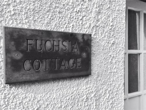 a metal sign on the side of a building at Fuchsia Cottage in Saint Mawes