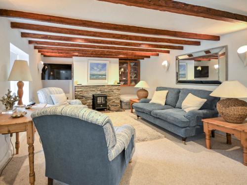 a living room with blue couches and a fireplace at Fuchsia Cottage in Saint Mawes