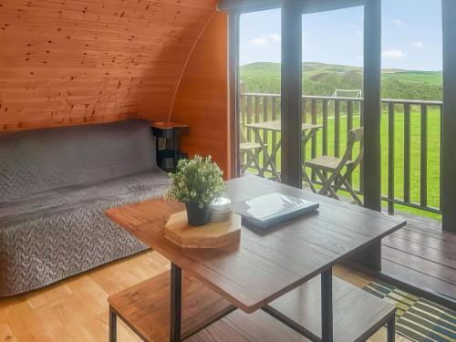 a living room with a table and a balcony at Pencaerau Pods - Tudwal Pod in Pwllheli