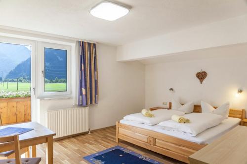 a bedroom with a bed and a table and a window at Ferienwohnung Sylvia in Ramsau im Zillertal