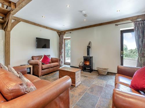 a living room with leather furniture and a fireplace at Y Llaethdy - Uk49916 in Penclawdd
