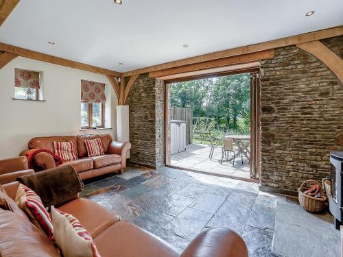 a living room with leather furniture and a stone wall at Y Beudy - Uk49917 in Penclawdd