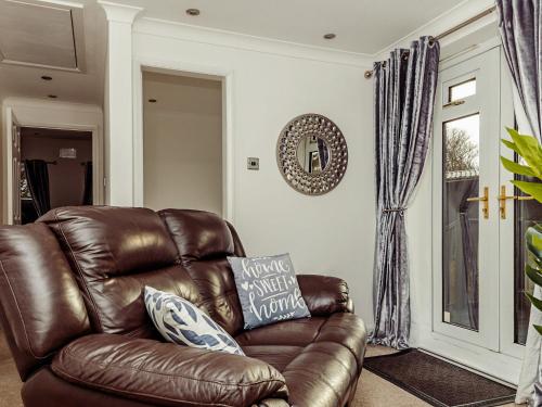 a brown leather couch in a living room with a window at Chalet 4 in Flookburgh