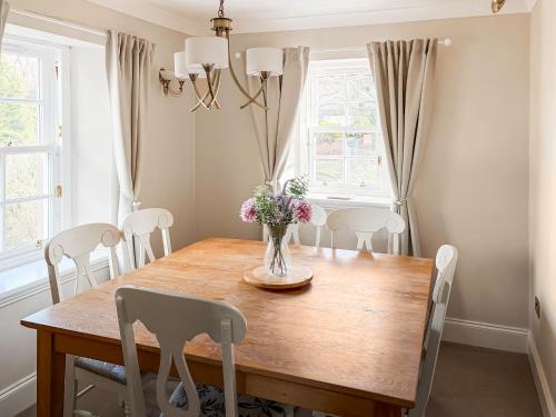 a dining room table with chairs and a vase of flowers at 2 The Langhouse in Inverkip