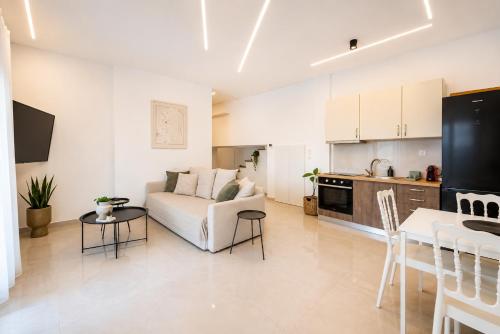 a living room with a white couch and a kitchen at Oasis Acropolis Serres Parking EV Next to Center in Serres