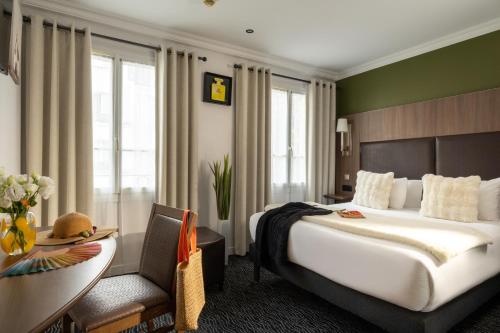 a hotel room with a large bed and a desk at Hotel London in Paris