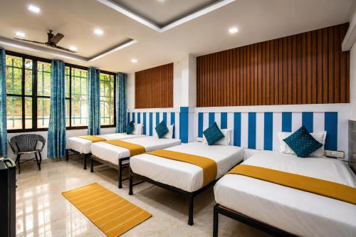 a row of beds in a room with windows at Hotel bright house in Calangute