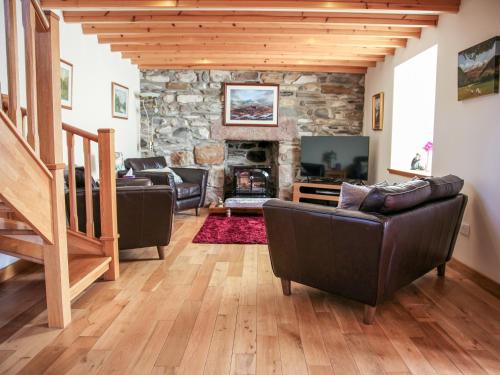 a living room with couches and a stone fireplace at Hill Cottage in Ardmair