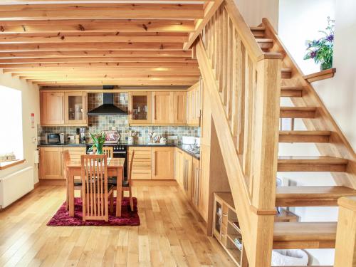 a kitchen with a wooden staircase and a table with chairs at Hill Cottage in Ardmair