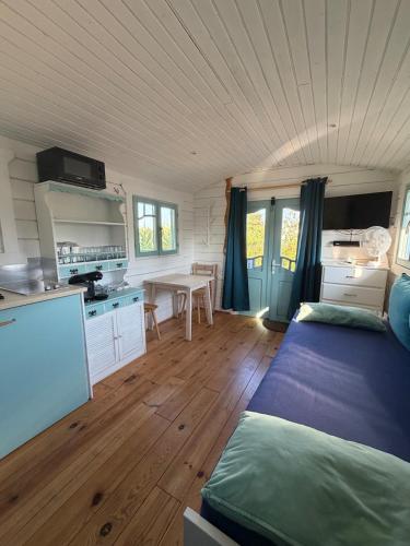 a room with a bed and a kitchen with a table at La Roulotte à Raven in Le Houga