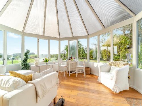 a living room with white furniture and windows at Torr Cottage in Dalrymple