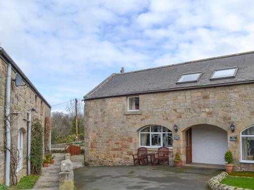 an old brick house with a patio in front of it at Waren View in Warenford