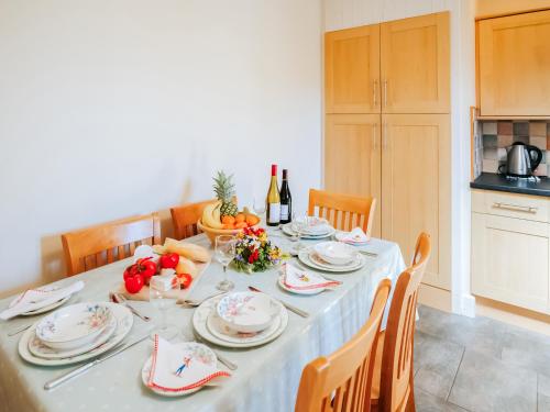 a table with plates and fruit and a bottle of wine at Cob Cottage in Rhossili