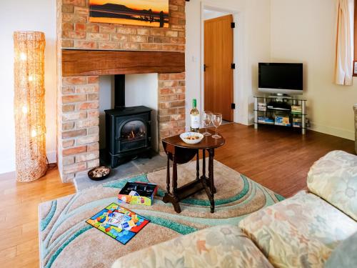 a living room with a fireplace and a table at Cob Cottage in Rhossili