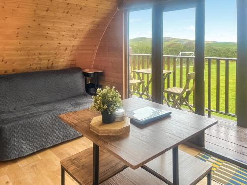 a living room with a couch and a table on a balcony at Pencaerau Pods - Enlli Pod in Pwllheli