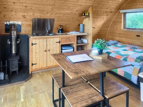 a room with a table and a stove in a cabin at Pencaerau Pods - Enlli Pod in Pwllheli