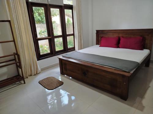 a bedroom with a bed with red pillows and a window at Bosadi Apartment katunayaka in Katunayaka