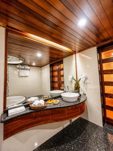 a bathroom with two sinks and a large mirror at Manuallaya The Resort & Spa in Manāli