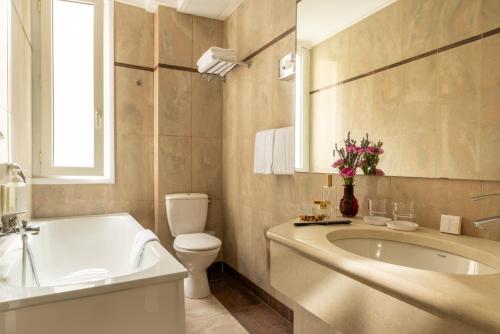 a bathroom with a tub and a toilet and a sink at Hotel London in Paris