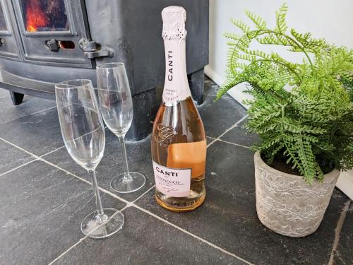 a bottle of wine and two wine glasses at Saddlers Cottage in Melrose