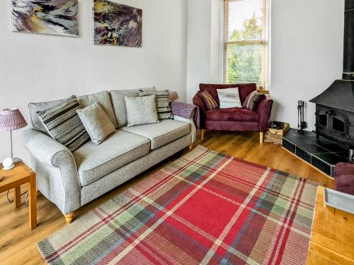 a living room with a couch and a chair at Saddlers Cottage in Melrose