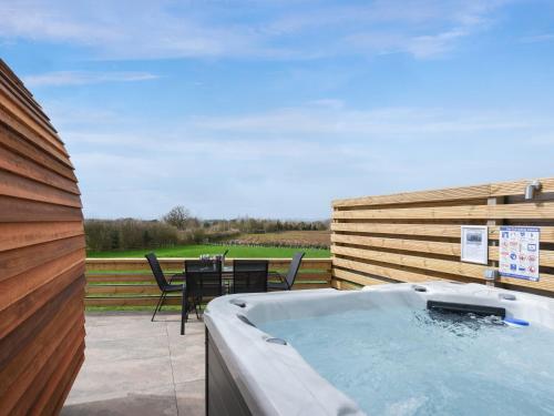 a hot tub on a patio with a table at Squirrels Retreat - Uk46127 in Nesscliffe